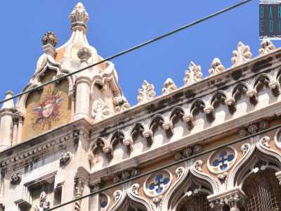 Particolare della facciata con il pinnacolo rappresentante il sol levante con le sembianze del dio Hermes